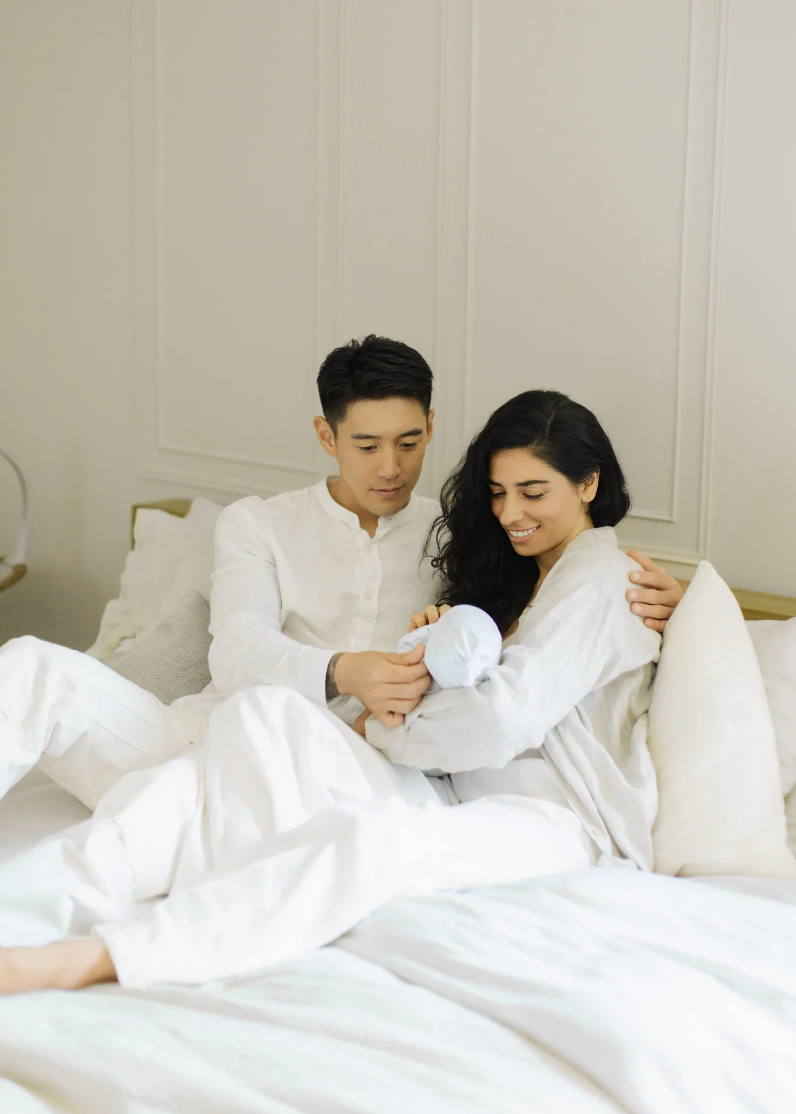 Parent at a kitchen table with a laptop open to a benefits portal, baby in carrier, calm morning light