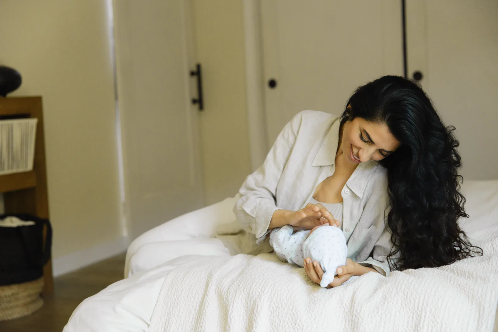 A new parent holding their newborn skin-to-skin in soft hospital light, baby's cheek resting against bare chest