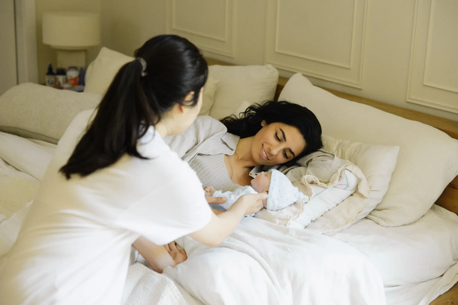 Parent holding newborn skin-to-skin in soft window light, baby's mouth wide open just before latching